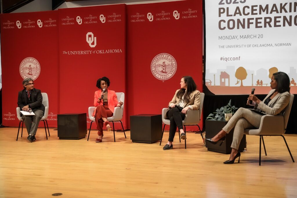 Three women and one man in conversation on a stage.